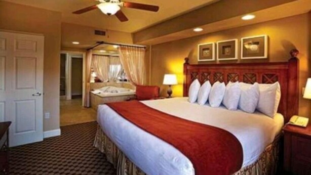 Habitación de hotel con una cama grande, un ventilador de techo y vista a la habitación contigua.