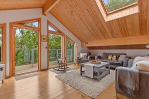 A spacious loft-style room with a high ceiling, large windows, and a cozy seating area. - Lodge 5 Longbury - Luxury Lodge Woodland Views Restaurant and Spa Facilites (Tenby)