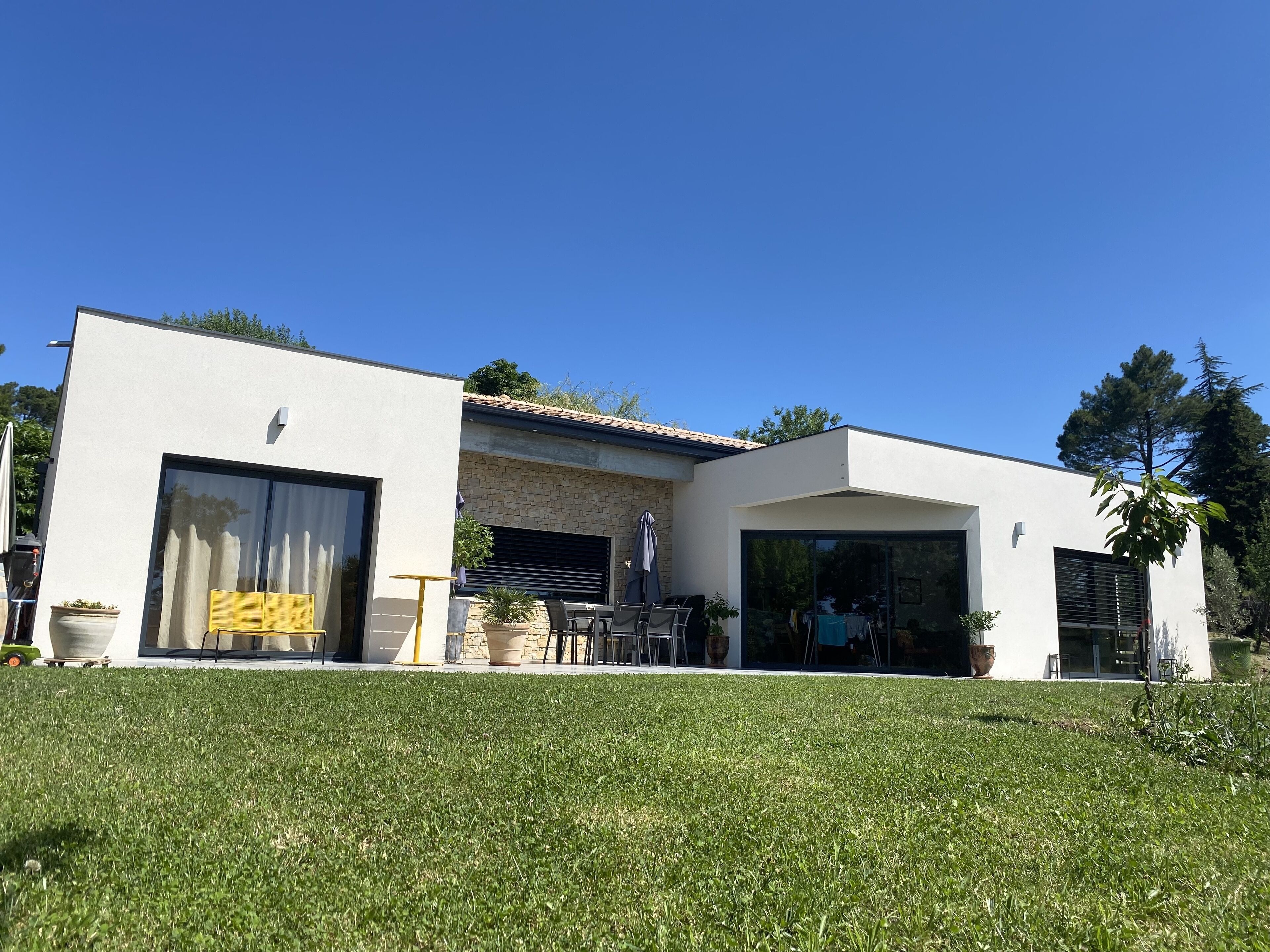 A modern house with a garage, patio, and a well-maintained lawn.