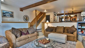 A living room with two sofas, a glass coffee table, and a staircase leading to a kitchen. - Ridge Retreat Breckenridge Townhome: Great Location, Views (Breckenridge)