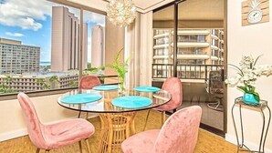 Moderni huone, jossa on lasipöytä, vaaleanpunaiset tuolit ja näkymä korkeisiin rakennuksiin.