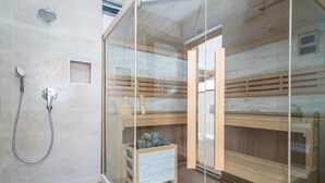 Una stanza sauna con pareti in vetro, panche di legno e un angolo doccia.
