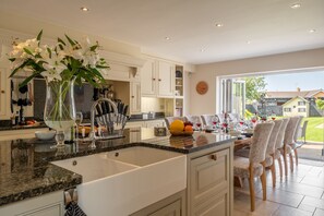 Une cuisine moderne dotée d’un grand îlot central, de meubles blancs et donnant sur le jardin.