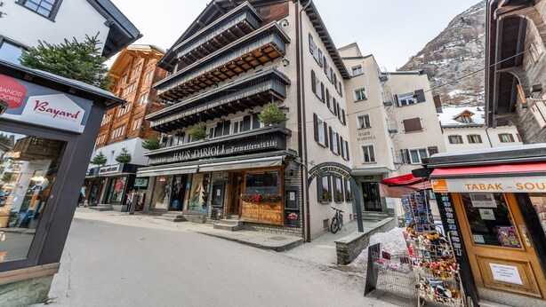 Une vue de rue avec un bâtiment portant l’inscription « Haus Darioli » et un magasin appelé « Bayard Sports Fashion ».