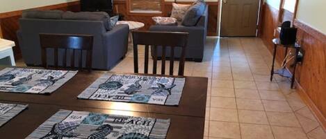 Un salon avec un canapé, deux fauteuils, une table basse et une porte au fond.