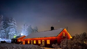 A snow-covered building with multiple windows and a red exterior, surrounded by snow-laden trees.