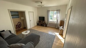 A living room with a sofa, a small table, a television, and a radiator.