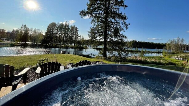 A hot tub with a view of a lake and trees.