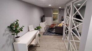 A modern living room with a white sofa, a wooden coffee table, and a potted plant.