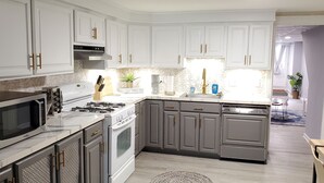 A modern kitchen with white cabinets, stainless steel appliances, and a central island.