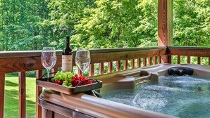 Een hottub met een houten terras, omringd door weelderige begroeiing.