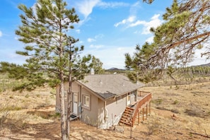 A single-story house with a small porch and a staircase leading to the entrance. - Falcon Ridge Chalet-Woodland Park: WiFi & Views, Deck and Views of Pikes Peak (Woodland Park)