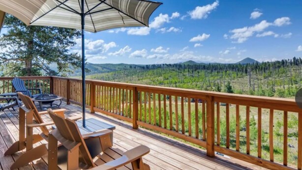 Eine Holzterrasse mit Gartenmöbeln und Blick auf eine bewaldete Landschaft.
