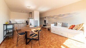 A compact living space with a dining area, kitchenette, and a sofa with decorative pillows. - The sound of the waves (Port-la-Nouvelle)
