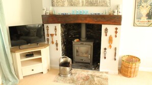 Un soggiorno con televisore su un mobile in legno, un caminetto con rivestimento in pietra e un elemento decorativo sopra.