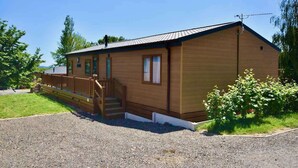 A single-story wooden building with a porch, a staircase, and a gravel driveway. - Rowan a welcoming countryside lodge (Ryde)