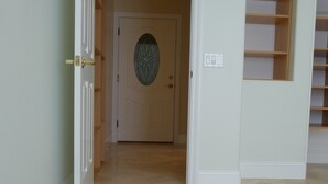Un umbral abierto que da a un cuarto con piso de baldosas y una puerta con un panel de vidrio decorativo.