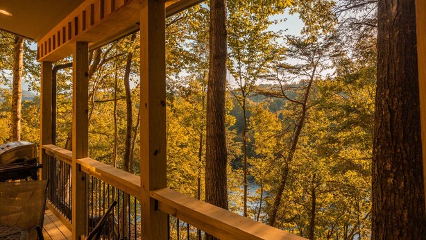 A wooden deck with a grill and chairs, overlooking a forested valley. - Bufflehead | Cabin on the South Holston River (Bristol)
