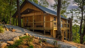 Eine Holzhütte mit geneigtem Dach, mehreren Fenstern und einem Steinfundament.