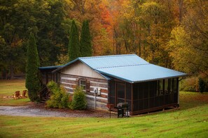 Une cabane rustique avec un toit en métal, des murs en bois et une véranda équipée de chaises.