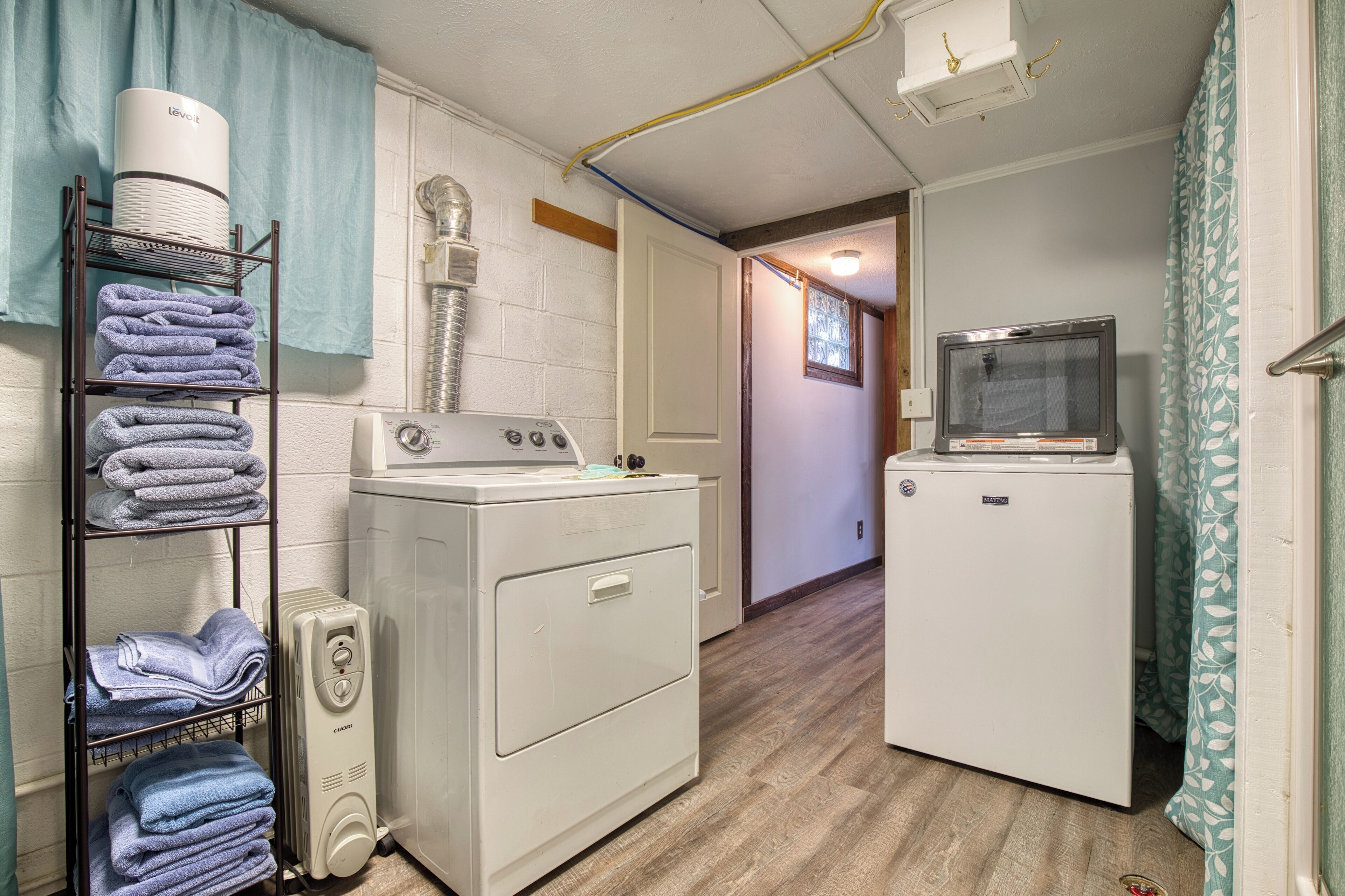 Une buanderie avec des piles de serviettes, un lave-linge à chargement frontal, un sèche-linge à chargement par le haut et un petit réfrigérateur.