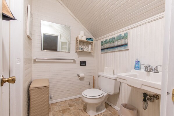 A bathroom with a toilet, sink, and a painting on the wall.