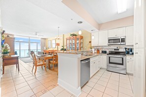 A spacious kitchen with white cabinetry, a central island, and a dining area with wooden chairs.