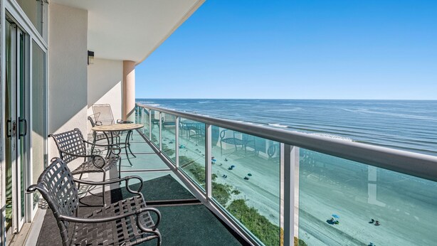 A balcony with a view of the sea, equipped with outdoor furniture and a glass railing. - Laguna Keyes PH 6 -Oceanfront 3BR-Amazing Views (North Myrtle Beach)