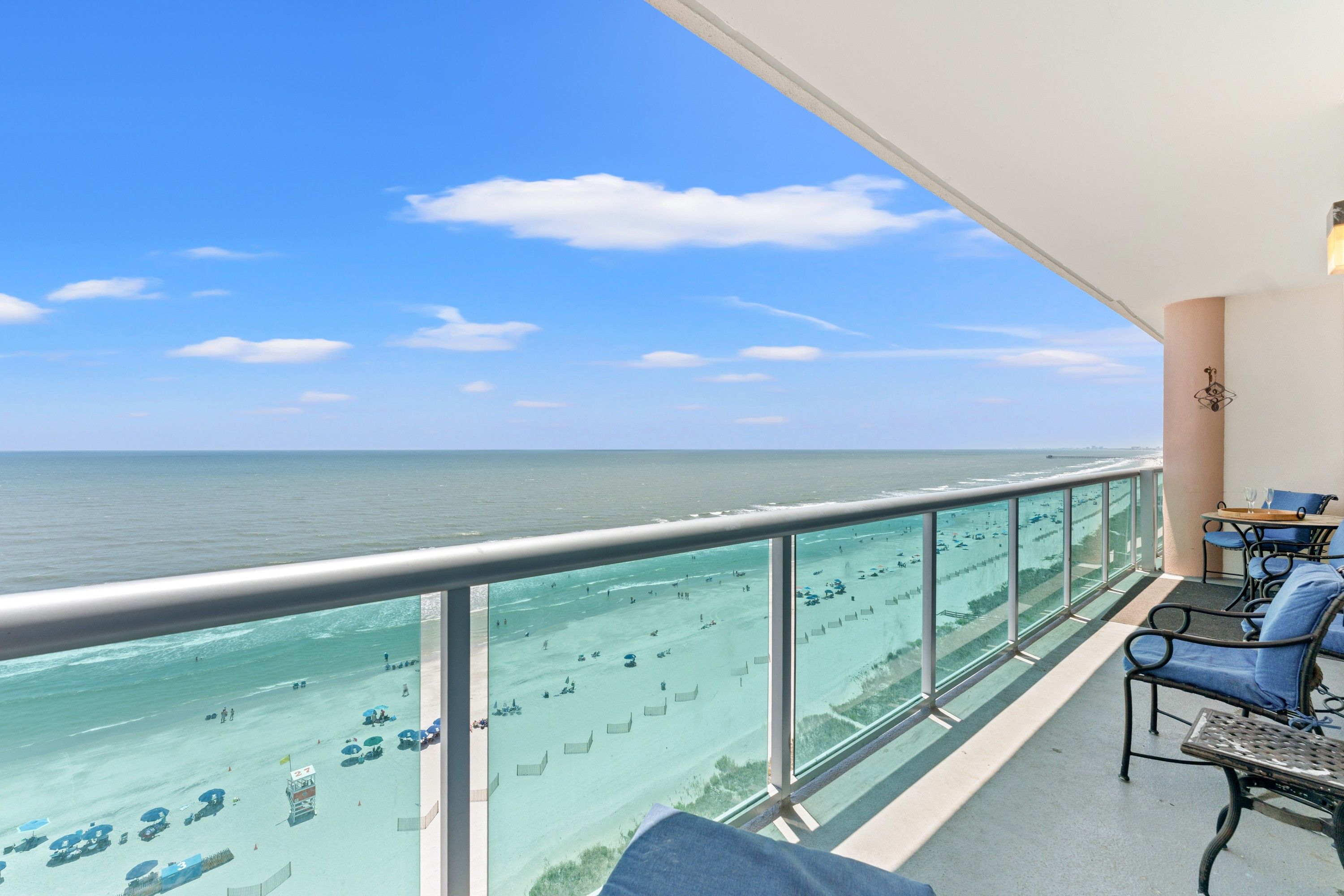 A balcony with a view of the beach and ocean.