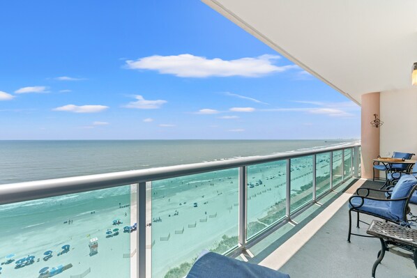 A balcony with a view of the beach and ocean.