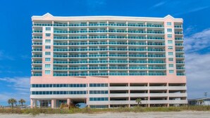 Un hôtel à plusieurs étages, doté d’un toit plat, de nombreux balcons et d’un parking situé à la base du bâtiment.