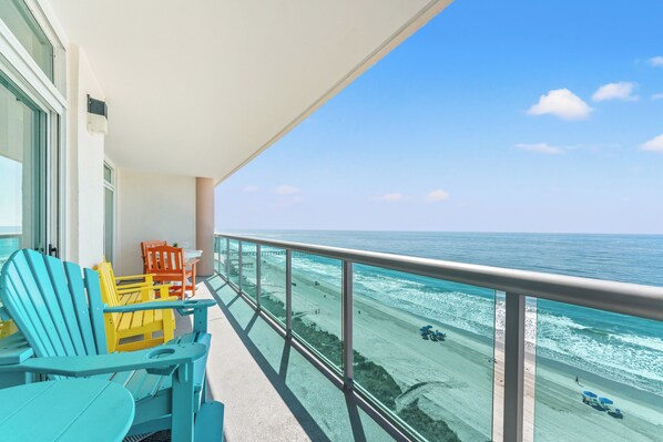 A balcony with a view of the ocean, featuring a table and chairs.