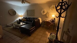 A living room with a sofa, coffee table, and a lamp. There is a coat rack and a chair in the corner. - Townhome:  2 Bedrooms, 2.5 Baths, Close to Campus (Oxford)