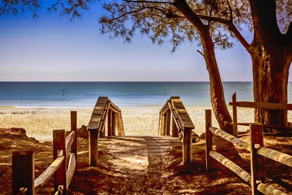 A wooden pathway leading to a beach with a clear view of the ocean.