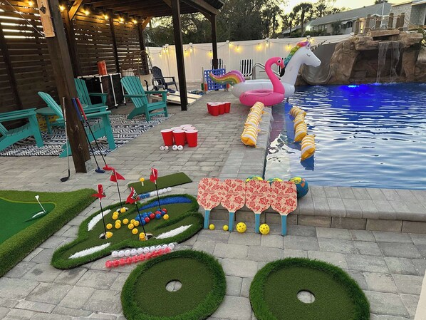 A backyard with a pool, inflatable flamingo, and a mini-golf setup. - *Charming 2bed 2 bath 6 mins from IMG* (Bradenton)