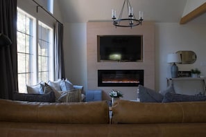 A living room with a fireplace, a sofa, and a TV mounted on the wall.