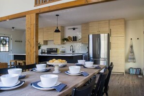 A modern kitchen with wooden cabinets, a stainless steel refrigerator, and a dining area with a wooden table set for four.