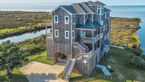 Ein mehrstöckiges Haus mit Balkon, Treppe und Blick auf das Wasser.