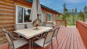 Eine Holzhütte mit einer Terrasse, Sitzgelegenheiten im Freien und Blick auf den Wald.