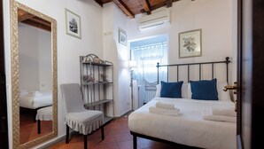 Un dormitorio con un espejo grande, una cama con almohadas azules, una silla y una estantería con flores.