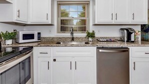 A modern kitchen with white cabinets, a built-in microwave, a stainless steel sink, and a dishwasher. - Private In-law suite in upscale neighborhood (Huntsville)