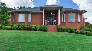 A two-story brick house with a front porch, a small front yard, and a clear sky. - Private In-law suite in upscale neighborhood (Huntsville)