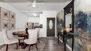 A dining area with a round table, chairs, and a vase of flowers. There is a kitchen in the background with cabinets and appliances. - Private In-law suite in upscale neighborhood (Huntsville)
