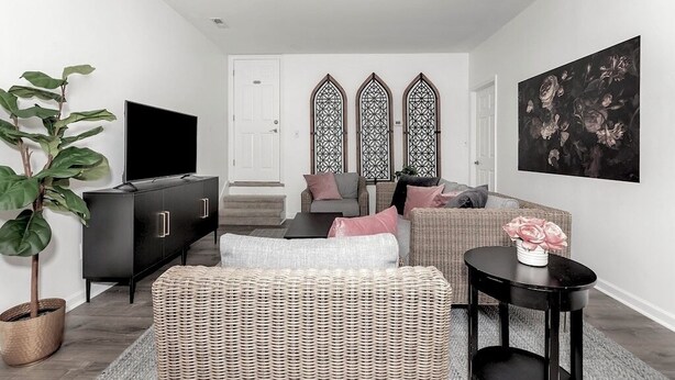 A modern living room with a black TV stand, wicker furniture, and a large painting on the wall. - Private In-law suite in upscale neighborhood (Huntsville)