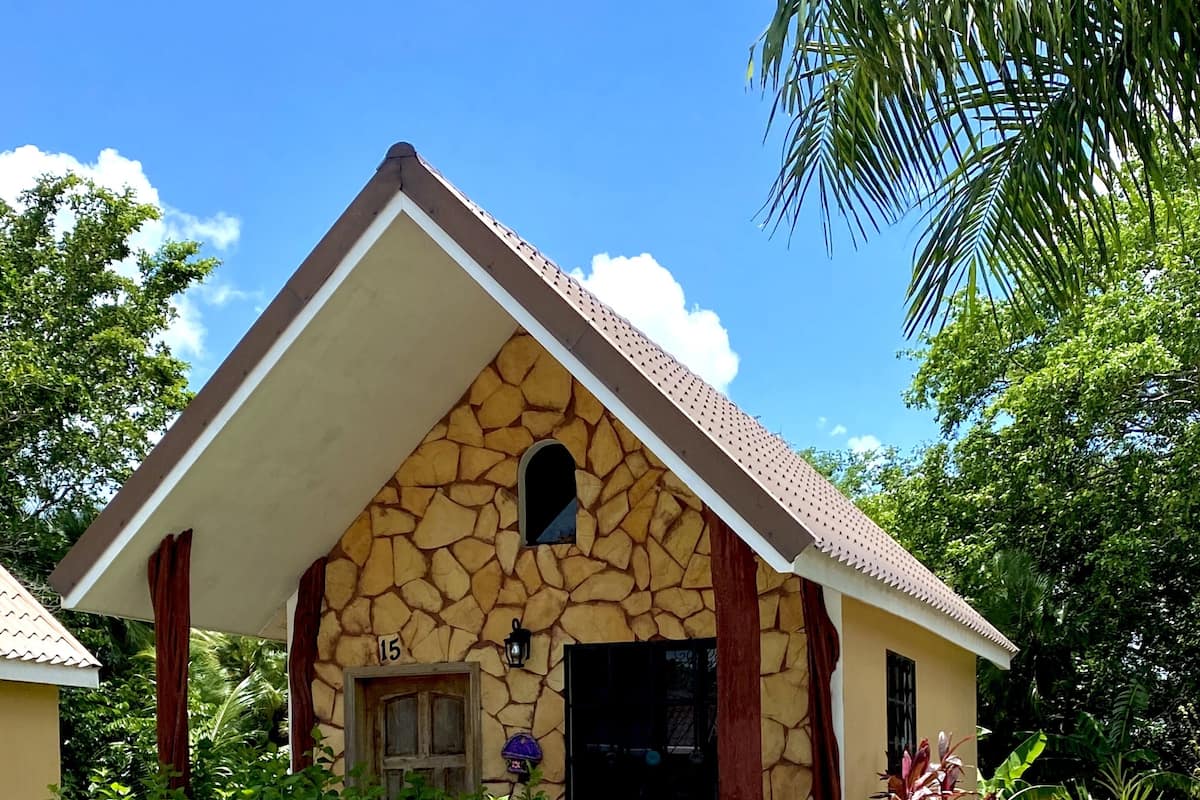 A stone house with a pitched roof, a small window, and a number '15' on the wall.