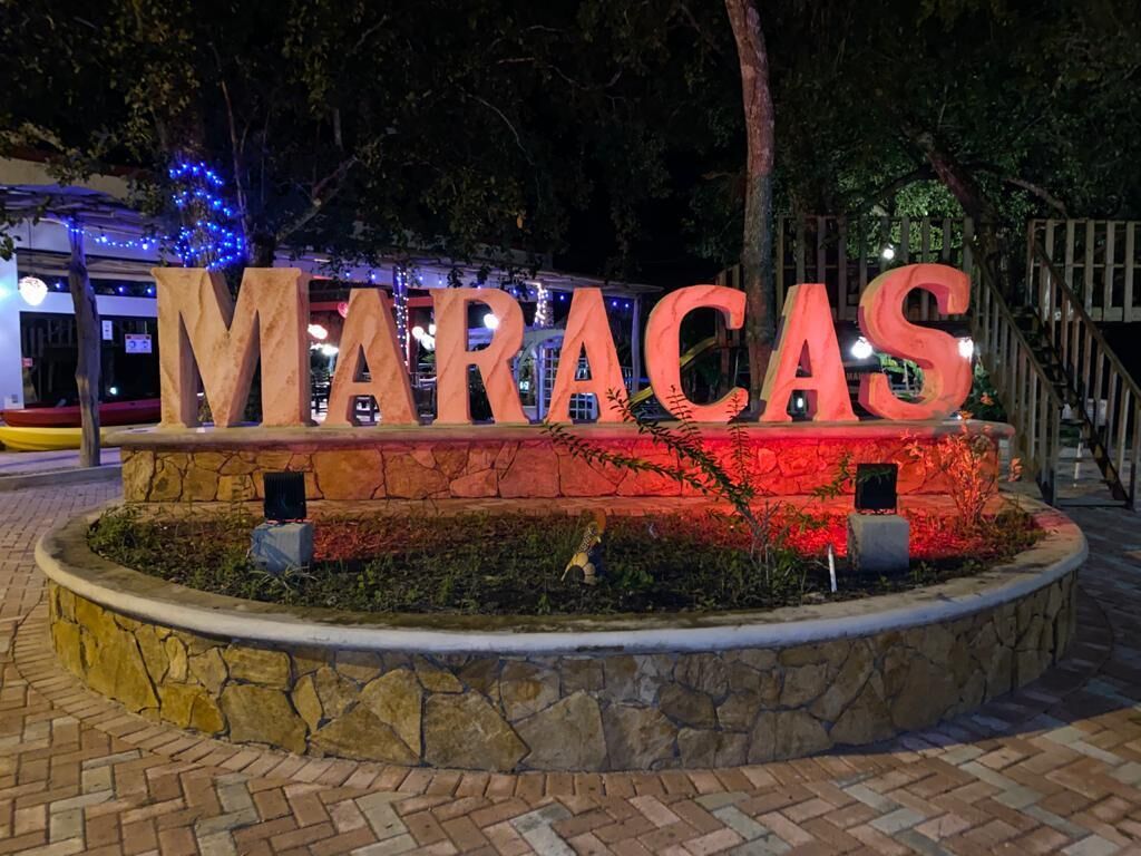 Un bac à fleurs en pierre sur lequel le mot « MARACAS » est inscrit en grandes lettres et illuminé.