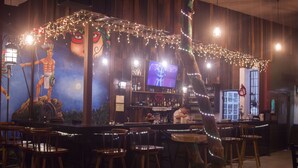 A bar area with wooden chairs, a television, and string lights. - El Gran Mestizo Resort (Orange Walk)