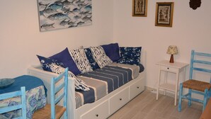 Une pièce comprenant un canapé-lit, deux fauteuils, une petite table et des œuvres d’art murales.
