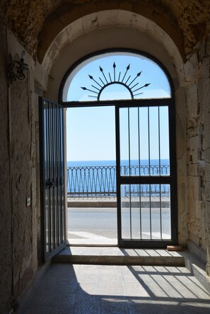 An arched doorway leading to a balcony with a metal railing overlooking the sea. - Le Petit Nice (Siracusa)