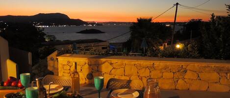 Une table à manger extérieure offrant une vue sur la mer et un magnifique coucher de soleil.
